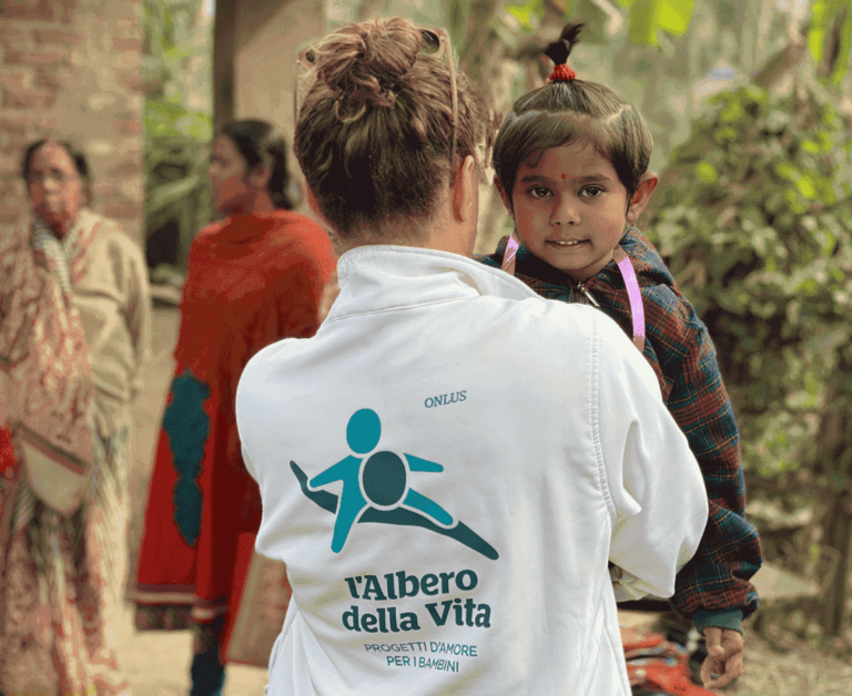 Una bambina in India presa in braccio da un'operatrice dell'Albero della Vita