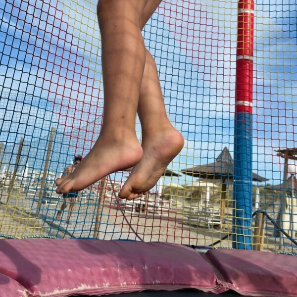 Bambina che salta su un tappeto elastico durante una giornata di gioco estiva, per la campagna vacanze della Casa dei Bimbi