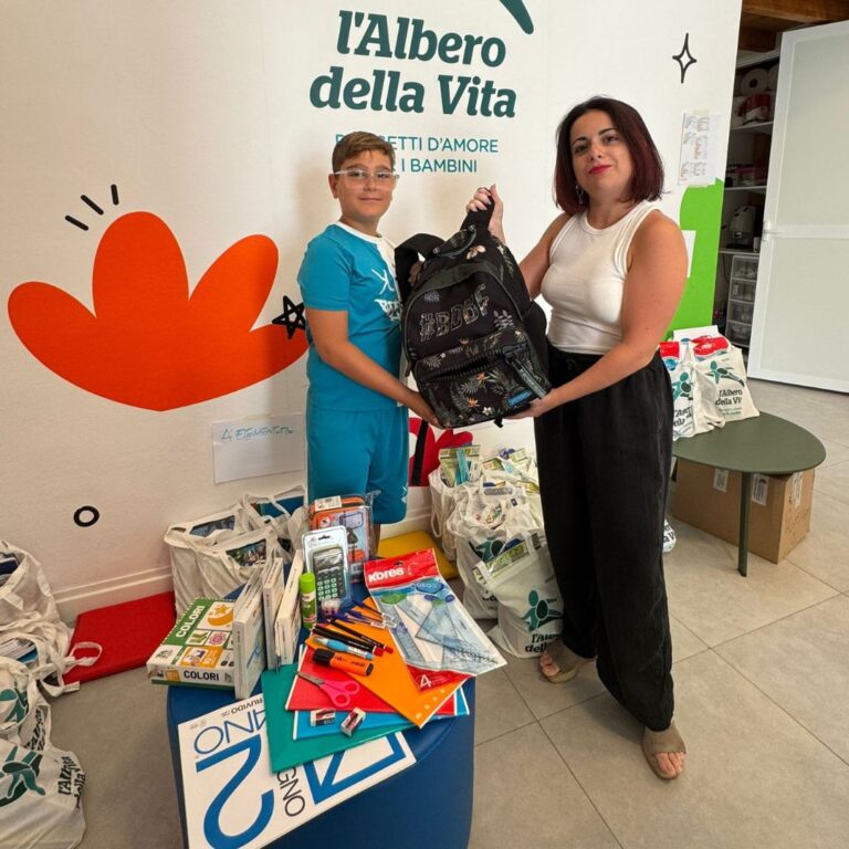 Bambino e adulta durante la consegna di uno zaino e materiale scolastico