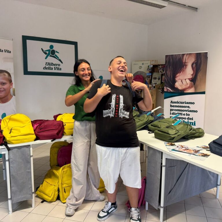 Ragazzo con zaino insieme a un’operatrice durante la preparazione dei materiali scolastici